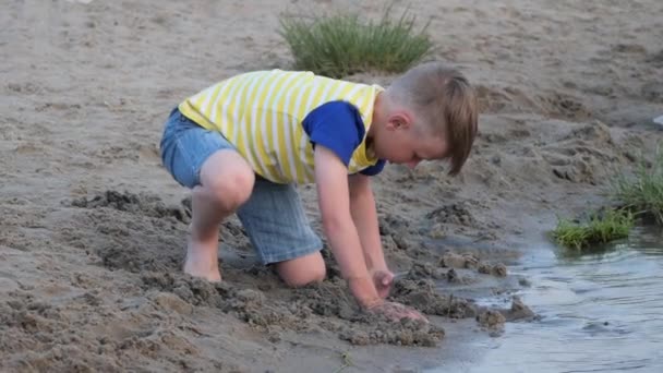 Chłopiec Bawi Się Piaskiem Plaży Pobliżu Wody — Wideo stockowe