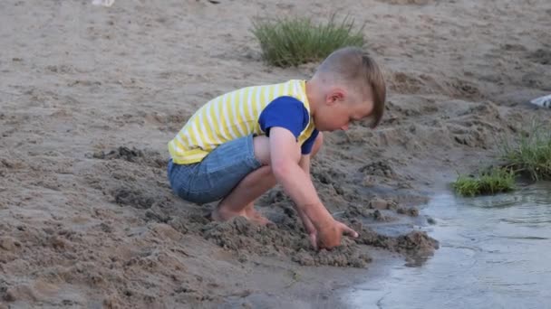 Αγόρι Παίζει Άμμο Στην Παραλία Κοντά Στο Νερό — Αρχείο Βίντεο