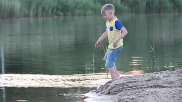 男孩晚上在海边靠近水的地方玩耍 — 图库视频影像