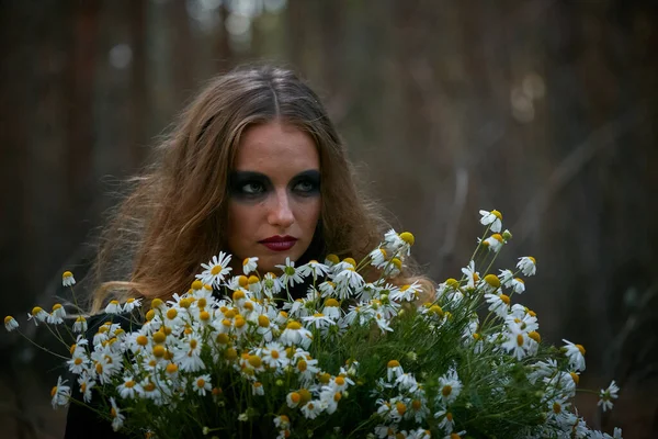 暗い松林の中にデイジーの花束を持つ魔女の女の子2020 — ストック写真