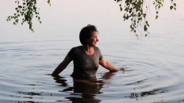 Güzel kız gün batımında bir gölde yıkanır.