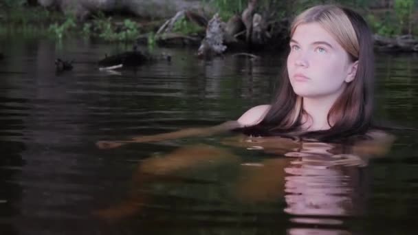 Meisje wordt weerspiegeld in het donkere water bij zonsondergang — Stockvideo