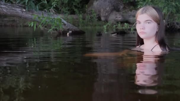 Девочка отражается в темной воде на закате — стоковое видео