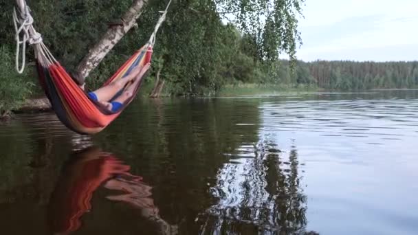 Niños oscilan en una hamaca sobre el agua del lago — Vídeos de Stock