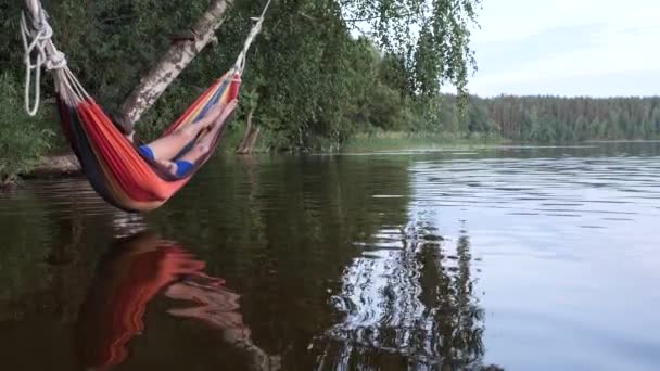 As crianças balançam em uma rede sobre a água do lago — Vídeo de Stock