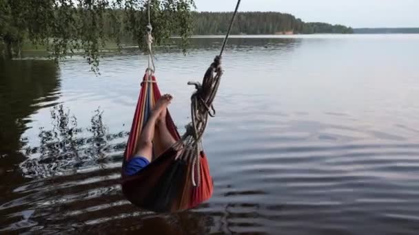 Niños oscilan en una hamaca sobre el agua del lago — Vídeo de stock