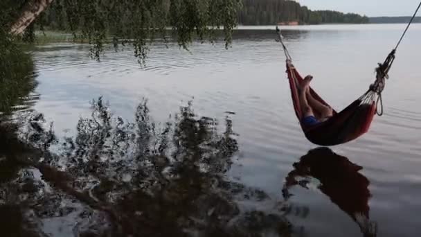 Enfants balancent dans un hamac sur l'eau du lac — Video