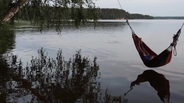 Barn svingar i en hängmatta över sjön vatten — Stockvideo