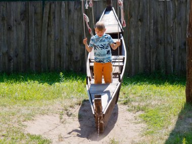 Çocuk 2020 model salıncak teknesine biniyor.