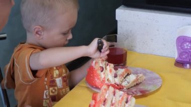 Küçük çocuk büyük bir dilim pasta yiyor.