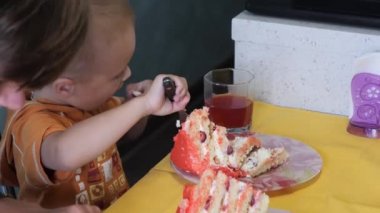 Küçük çocuk büyük bir dilim pasta yiyor.