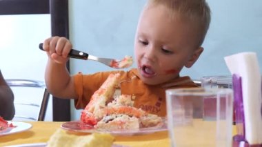 Küçük çocuk büyük bir dilim pasta yiyor.