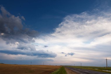 Bulutlu mavi gökyüzünün altındaki bir arazide yol 2020