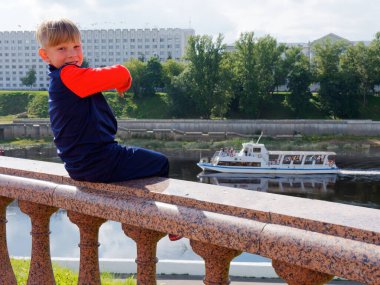 2020 rıhtımındaki korkulukta oturan çocuk.