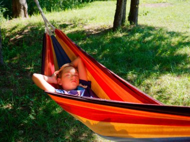 2020 ağaçlarının gölgesinde bir hamakta sallanan çocuk.