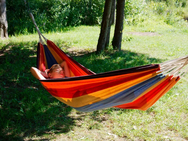 2020 ağaçlarının gölgesinde bir hamakta sallanan çocuk.