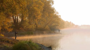 Erkekler yaz sabahı oltayla nehirde balık tutuyor. Güzel sis. 2020