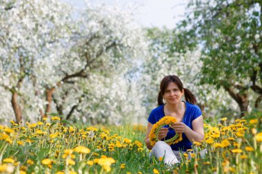 2020 'de çiçek açan elma bahçesindeki kadın ve karahindiba tarlası.