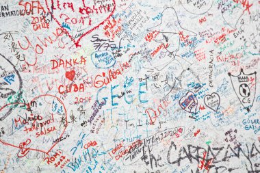 Bir sürü kırmızı ve mavi duvar yazısı olan beyaz bir duvar.