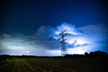Bir fırtınanın önündeki elektrik hatları bir tarlanın üzerinde. Yüksek kalite fotoğraf. Mavi gökyüzü, mavi bulutlar 