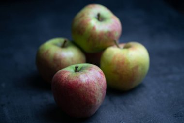 Siyah arkaplan önünde beş kırmızı ve yeşil elma