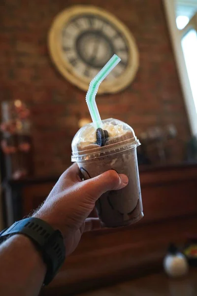 Bir adamın elinde pipetle milkshake.