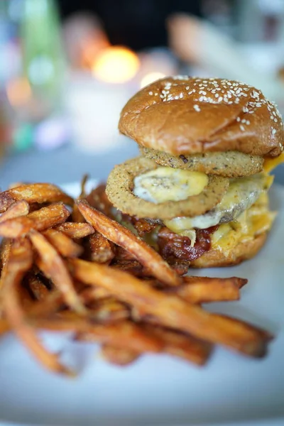 Burger with onion rings eggs bacon and sweet potatoe fries Royalty Free Stock Photos