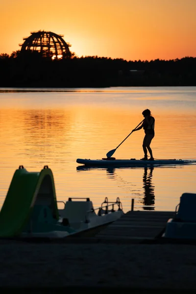 Gün batımının önündeki gölde kürek çek.