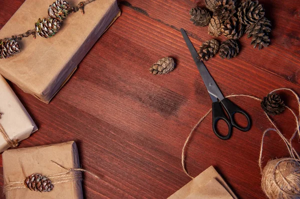 Tahtanın üzerinde çam kozalaklı makas ile el yapımı karton kutular.