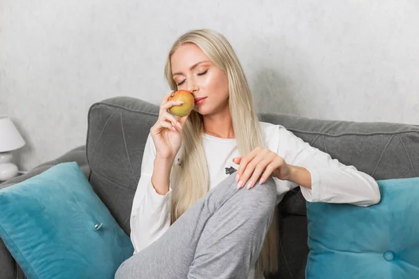 ソファでリンゴを食べる女性 — ストック写真