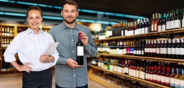 Alkol perakendecisi kavramı. İş sahipleri kadın ve erkek dükkanlarındaki şarap şişelerinin önünde gülümserler..