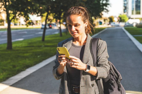 Grainy textured photography of modern urban woman using her smartphone on city street.