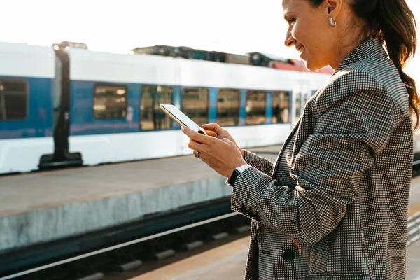 Woman commuter using her mobile phone on railway platform