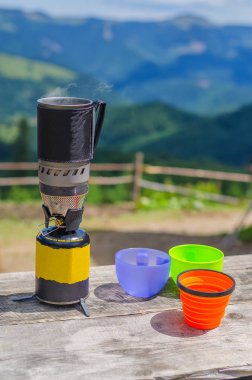 dağlarda plastik gözlüklü çelik kupa bir gaz sobası