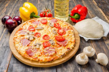 Ev yapımı pizza domates ve mantarlı sebzeli ahşap bir masa üzerinde