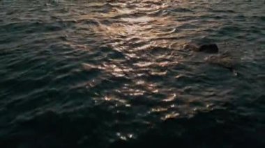 Gün batımında ufka doğru eğilerek denizin üzerinde ilerleyen hava hareketleri.