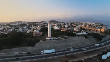 Deniz feneri denize doğru geri hareket ederken şehrin havadan görüntüsü.