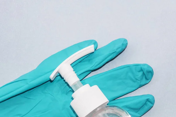 Top-down view sanitizer anti-sentic medical liquid and anti-coronavirus COVID-19 in plastic pump press head white transparent bottle on blue disposable glove
