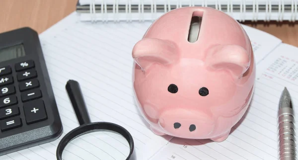 Piggy Bank, calculadora, lupa y bolígrafo en el organizador para la planificación de negocios. Concepto empresarial de ahorro financiero —  Fotos de Stock