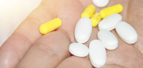 Palma aberta de uma mulher com um monte de pílulas brancas e rosa, conceito de saúde e medicina, close-up — Fotografia de Stock