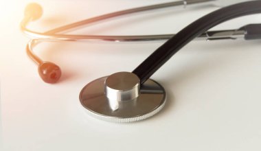 Tıbbi bir steteskop yakın plan beyaz arka planda, ışık efektli, tıp konsepti.