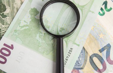 Avro ve Amerikan dolarlarının banknotları üzerinde duran büyüteç, finansal yönetim kavramı