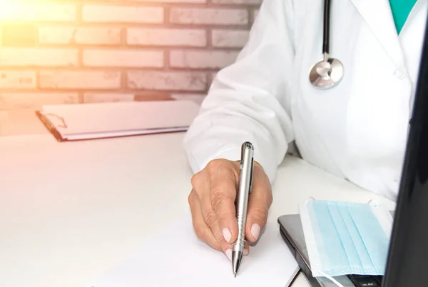 Egy női orvos laptopon dolgozik, és feljegyzéseket ír a betegnek egy orvosi vizsgálatról vagy receptről. — Stock Fotó