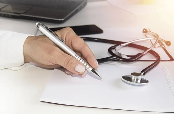 Kobieta lekarz pisze notatki o badaniu lekarskim lub recepty, zbliżenie ręki — Zdjęcie stockowe