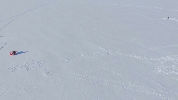 Зимнее веселье. Люди на замерзшем озере занимаются парапланеризмом и зимней рыбалкой — стоковое видео