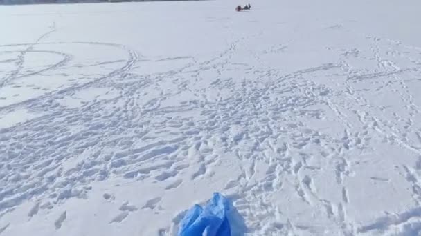 冬の楽しみ。凍った湖の上の人がパラグライダー、冬の釣りに従事しています。 — ストック動画