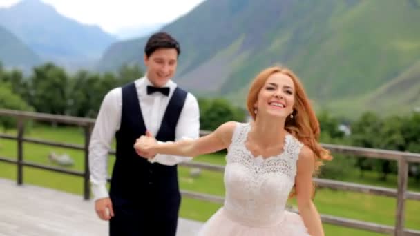 Hochzeitstag. glückliches Brautpaar hat Spaß vor der Bergkulisse. — Stockvideo