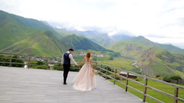 Felices recién casados en un fondo de montañas el día de su boda. Sesión de fotos de boda. Georgia — Vídeo de stock