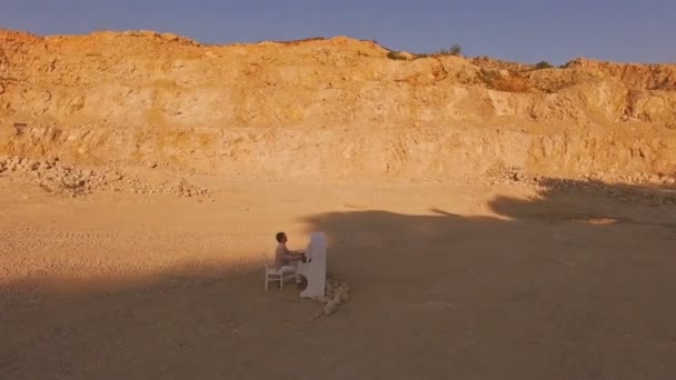 Homme joue sur un piano blanc au bas d'une robe jaune. Vue d'en haut. Vue aérienne . — Video