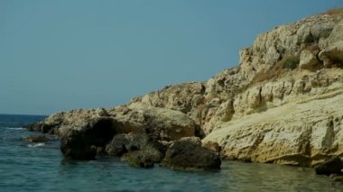 Şeffaf deniz mavi su taş sahile yıkar. Yunanistan